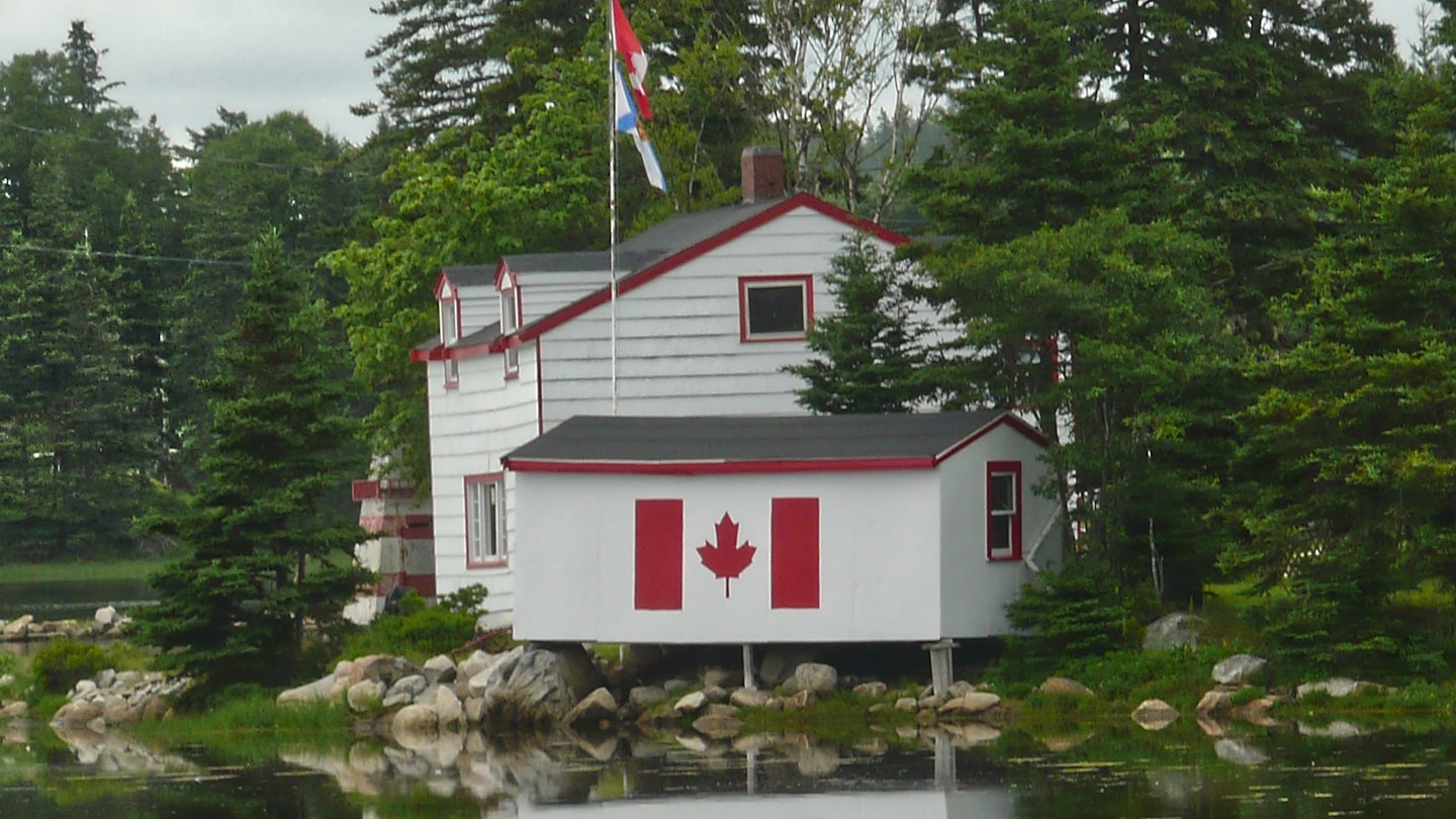 Photo d'ambiance d'un petit chalet blanc et rouge au bord de l'eau
